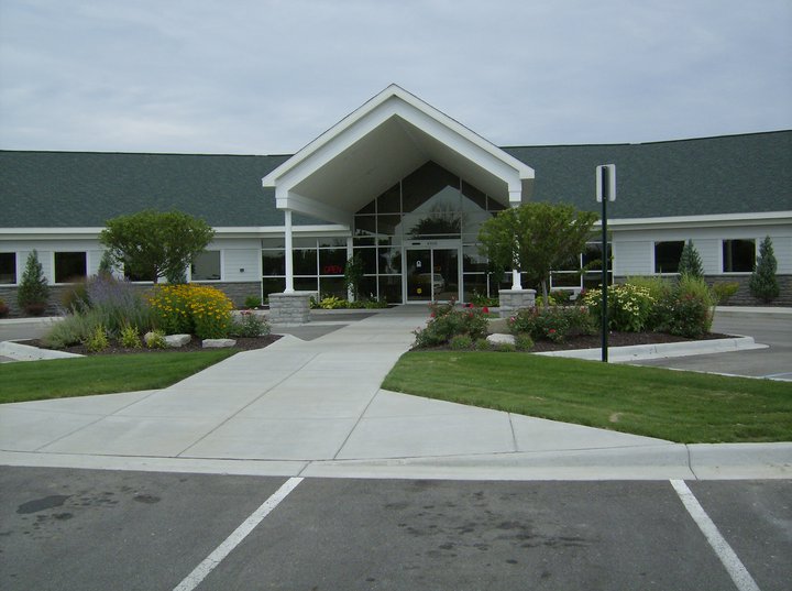 Isabella Urgent Care exterior on East Bluegrass Road in Mt. Pleasant, Michigan &mdash; peaked entry portico, green landscaping, open pathway to the front door.